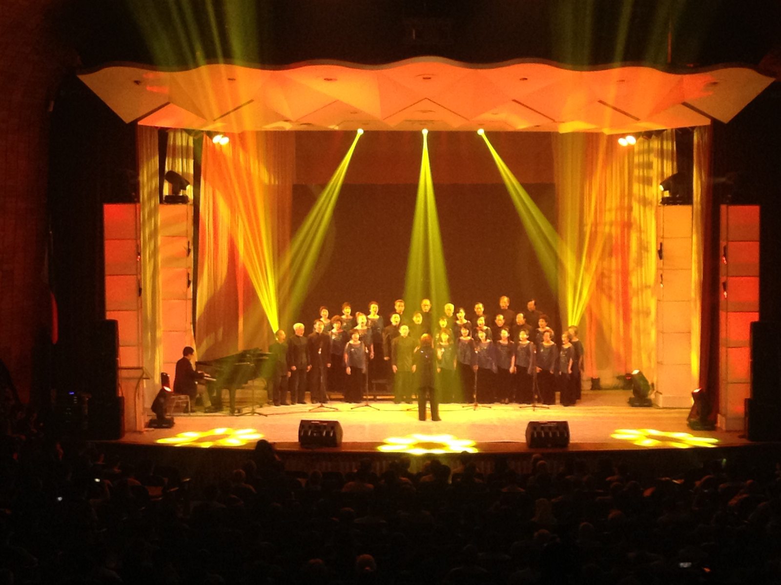Choir illuminated by warm amber stage light and narrow yellow beams